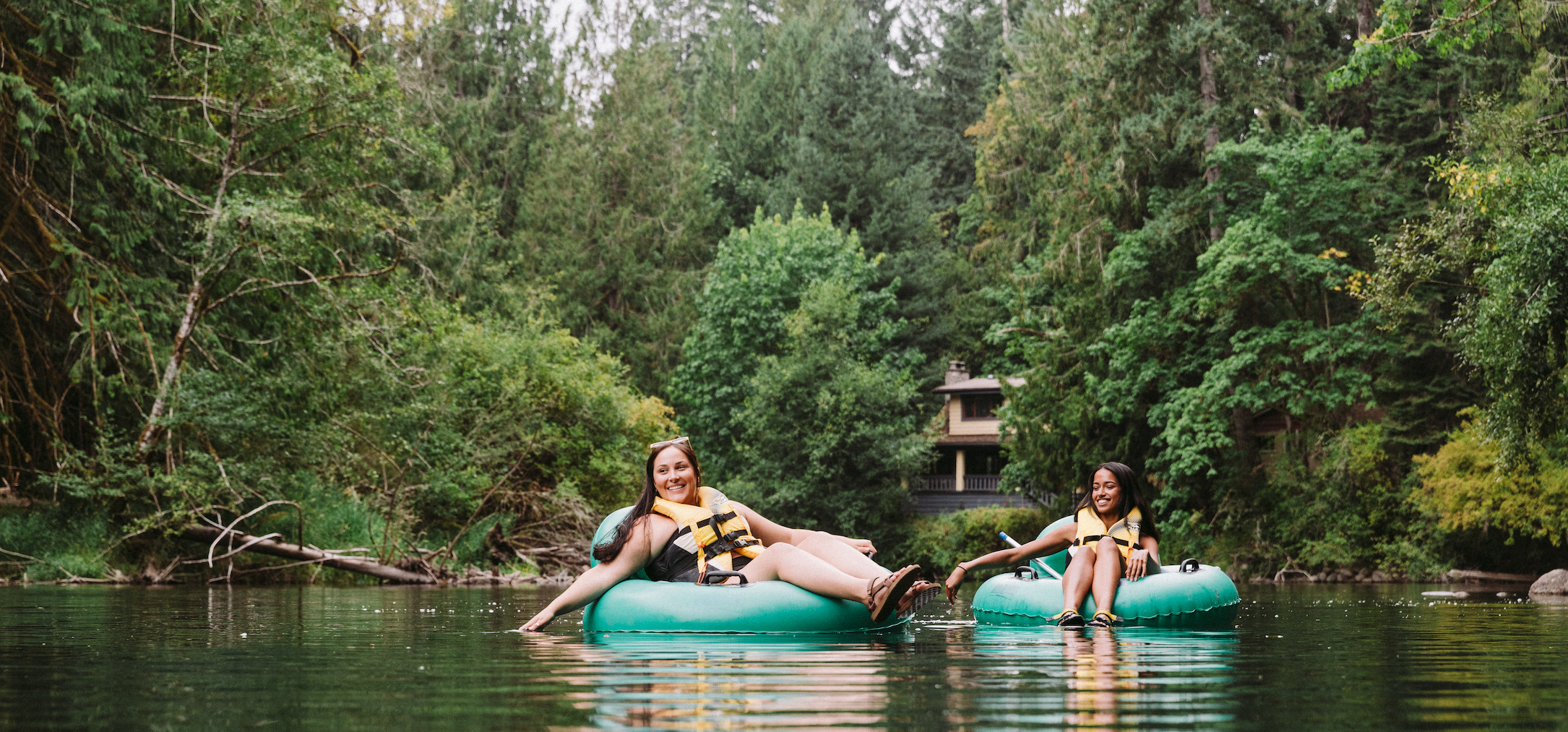 two people tubing down a river with trees in the background
